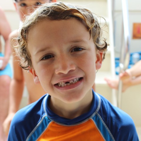 Young boy with a missing tooth smiles for the camera aboard a private glass bottom boat ride