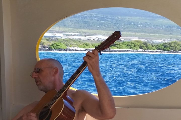 a person with a guitar in front of a body of water