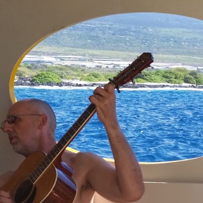 a person with a guitar in front of a body of water