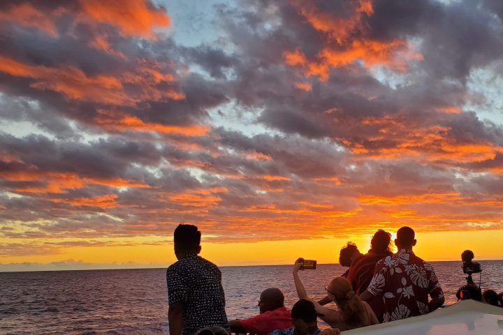 a group of people standing in front of a sunset